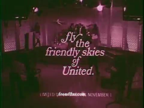 The still features a vintage 1970s game show set with vibrant lighting. In the foreground, bold text reads, “fly the friendly skies of United,” promoting United Airlines. The background suggests a lively atmosphere typical of game shows from that era, with potential contestants or audience members present. There's also a mention of a limited time offer, adding urgency to the advertisement. The overall aesthetic captures the nostalgic charm of 1970s television commercials.