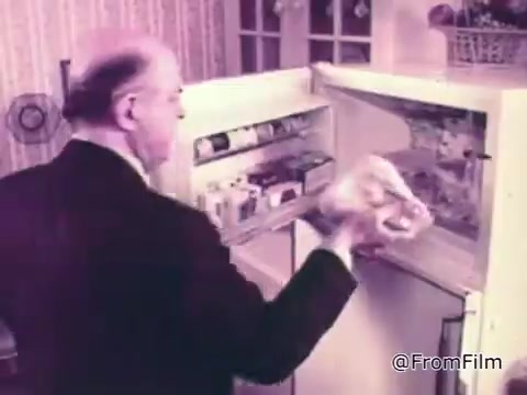 In the still from the 'Baggies Alligator Storage Bags' commercial, a man is seen reaching into a refrigerator. He appears to be handling a chicken wrapped in Baggies Alligator storage bags. The setting has a vintage feel, with a cozy kitchen background. The emphasis is on the durability of the bags, highlighting their ability to protect food from freezer burn. The alligator motif suggests toughness and reliability in food storage.