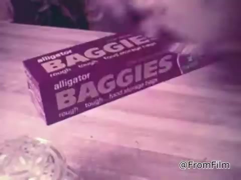 The still features a box of 'Baggies Alligator Storage Bags' prominently displayed on a table, suggesting a focus on food storage. The box is brightly colored with bold lettering emphasizing its protective qualities. This scene likely aligns with the product's advertising message about preventing freezer burn and providing tough protection for food items, underscored by the playful mention of an alligator as a tough, memorable character.