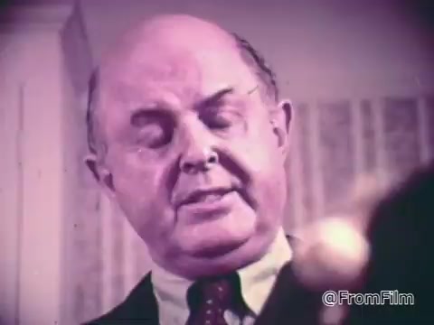 The still features a man in a suit with a serious expression, likely portraying an authority figure. He appears to be discussing the Baggies alligator storage bags while emphasizing their effectiveness in preventing freezer burn. The background suggests a domestic setting, aligning with the commercial's focus on household products. The color palette has a vintage tone, typical of commercials from earlier decades.