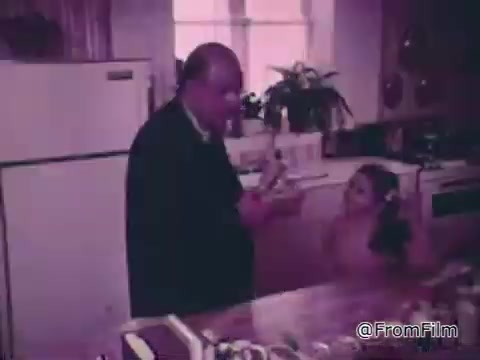 The still from the 'Baggies alligator storage bags' commercial features a man and a child in a kitchen setting. The man appears to be demonstrating or discussing the storage bags, likely emphasizing their durability and effectiveness against freezer burn. The atmosphere is casual, with the child seemingly engaged in the conversation. The kitchen displays common household items, contributing to a relatable, family-oriented vibe.