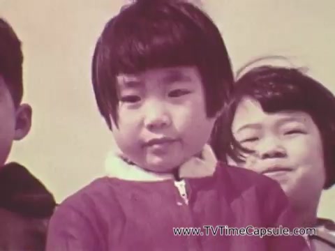 The still from the 'Christian Children's Fund PSA' features several children, prominently showing a young girl in the foreground. She has a bob haircut and is wearing a bright jacket. The background includes other children who appear to be smiling. The overall tone of the image is warm and engaging, typical of public service announcements aimed at highlighting children's needs and promoting support for their welfare.