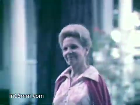 The still from the 'Breyers Ice Cream Ad - 1980's' features a woman walking with a warm smile. She appears to be reminiscing about her childhood and the quality of Breyers ice cream, which she compares to homemade varieties. The scene conveys nostalgia and emphasizes the natural ingredients of the product, aligning with the ad's message about purity and simplicity. The color palette suggests a soft, vintage feel.