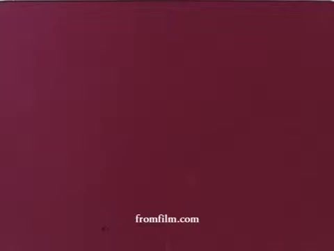The still from the 'Muscular Dystrophy PSA: No Strings' features a plain, deep red background. Given the context of a 1970s public service announcement, it likely aims to evoke emotion and awareness around muscular dystrophy, encouraging viewers to contribute to the cause, possibly through donations or volunteer efforts linked to Jerry Lewis. The fading quality, typical of vintage film, suggests age and deterioration, impacting visual clarity. Overall, the image presents a somber tone that aligns with the serious message of the PSA.