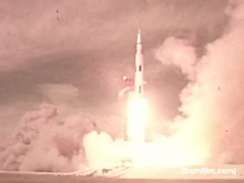 The still captures a moment from the launch of a Saturn V rocket, characterized by a dramatic plume of smoke and flames as the rocket lifts off. The image is tinted with a vintage aesthetic, typical of 16mm film, highlighting the power and intensity of the launch. The context suggests a connection to the Apollo 17 mission and indirectly to Pepperidge Farms, emphasizing the brand's involvement in space missions through its bread products.
