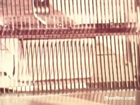 The still from the 'Pepperidge Farms - Apollo 17' commercial features a close-up view that likely captures a bread storage compartment or a food preparation area. The visual is characterized by a grid-like pattern, possibly created by metal grates or racks. The warm, vintage color tone reflects the 16mm film aesthetic, emphasizing a nostalgic feel. The absence of voiceover suggests a focus on the imagery, possibly highlighting the connection between Pepperidge Farms bread and the space missions. Overall, the shot conveys a sense of innovation and quality associated with the brand.