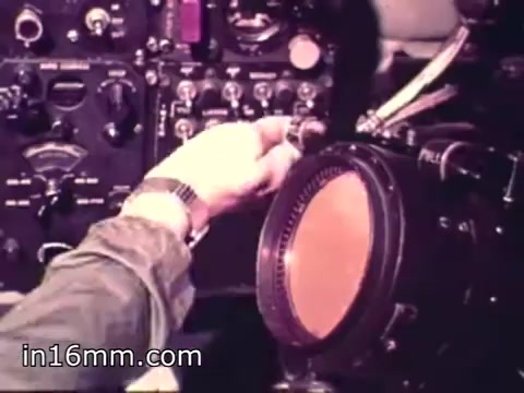 The still from 'Air Force Reserve Recruiting - 1968 - Air Crews' depicts a close-up of a hand adjusting a control on an aircraft's dashboard. The cockpit environment features various instruments and gauges, highlighting the technical aspects of being part of an air crew. The focus on the controls emphasizes the precision and responsibility involved in aviation, aligning with the recruiting theme of the film.