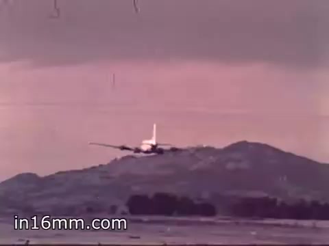 The still from 'Air Force Reserve Recruiting - 1968 - Air Crews' depicts an aircraft in flight, possibly approaching to land. In the background, there are mountains and a cloudy sky, indicating a rugged landscape. The image captures the essence of military aviation, focusing on the aircraft's operational environment. The colors suggest a vintage aesthetic typical of the late 1960s.