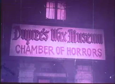 The still features a dimly lit exterior shot of 'Dupree's Wax Museum,' prominently displaying a sign that reads 'CHAMBER OF HORRORS.' The atmosphere is eerie, with a sense of foreboding, enhanced by the muted colors typical of a vintage 16mm print. The overall composition sets a suspenseful tone appropriate for a horror film trailer.