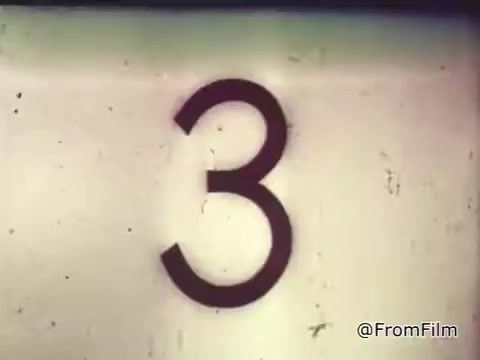 The still features a large, bold number '3' against a faded background, indicative of a countdown sequence. It likely serves as a prelude to the commercial, capturing the vintage aesthetic of 1960s film with subtle imperfections characteristic of a 16mm print. The context relates to a Chase and Sandborn Coffee advertisement featuring race car driver Roger McClusky, emphasizing excitement and speed linked to the product.