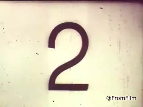 The 16mm still likely features a large, aged numeral '2' as part of the countdown or scene transition in the commercial. This reflects the vintage aesthetic of the 1960s, emphasizing the era's film style. The context indicates that it is part of a Chase and Sandborn Coffee commercial featuring race car driver Roger McClusky, set against a backdrop of excitement typical of auto racing and marketing of that time.