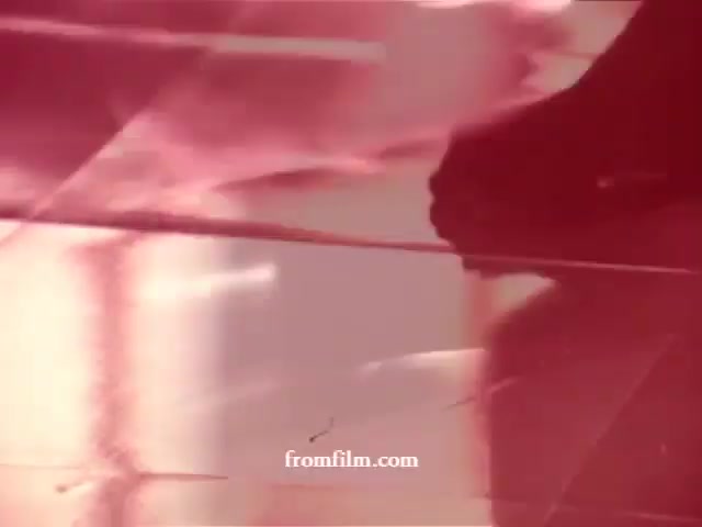 The still features a vibrant, abstract composition that likely showcases cleaning products in action, highlighting their effectiveness on surfaces. The colors are bright with a predominance of pink and red hues. The image may capture dynamic movement or spray patterns, evoking a sense of freshness and cleanliness. The visual style reflects the nostalgic charm of vintage commercials, encapsulating the era of its production.