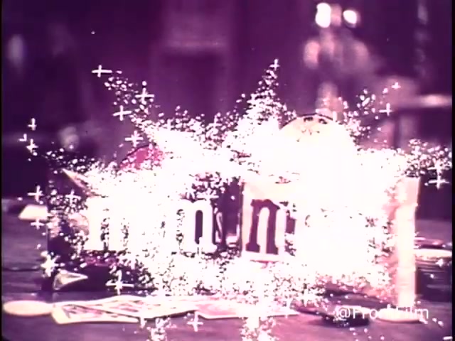 The still from the 1970s M&M's commercial showcases a dynamic and colorful display. The iconic M&M's logo is prominently featured, surrounded by playful sparkles and a whimsical atmosphere. Candy wrappers are scattered across a table, suggesting interactive fun, likely referencing the game 'Go Fish' mentioned in the ad. The presence of a red M&M indicates this commercial is pre-1976, as red was replaced by orange due to health concerns surrounding red dye. The tagline emphasizes enjoyment associated with M&M's chocolate candies, both plain and peanut.