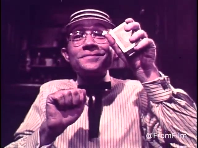 The still from the 1970s animated M&M's commercial features a cheerful character, likely an old-fashioned card dealer or game host, holding a pack of M&M's. He has a playful expression, emphasizing the fun associated with M&M's candies. The commercial promotes M&M's as a source of 'good, clean fun' and highlights both plain and peanut varieties. The inclusion of the red M&M indicates that this was produced before 1976, when the red dye was discontinued. The overall tone is lighthearted and inviting, aimed at encouraging viewers to enjoy M&M's during recreational activities.