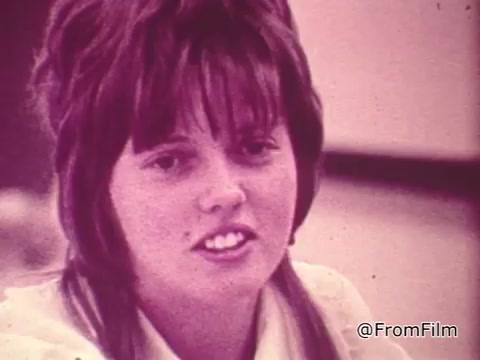 The still features a young woman speaking about the benefits of TouchTone phones, part of a Chesapeake and Potomac Telephone commercial. She likely conveys enthusiasm about the technology's ease of use compared to rotary phones, highlighting advantages such as quicker dialing and improved connectivity. The visual style suggests a vintage, possibly warm color palette typical of 16mm film from that era.