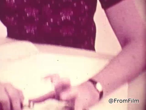 The still likely features a close-up of a person's hand interacting with a TouchTone phone, emphasizing its ease of use compared to rotary phones. The context suggests a discussion on the benefits of TouchTone technology, highlighting quicker dialing and improved functionality. The overall aesthetic may reflect the era's style and color grading typical of 16mm film.