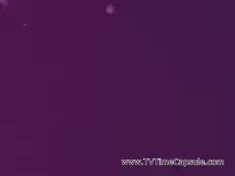 The still from the 'ScottTowels Commercial' features a vivid purple background, possibly with a soft gradient. The image has subtle specks of light or texture, contributing to a dynamic visual effect, likely intended to catch the viewer's attention. The overall composition suggests a focus on branding or product presentation in a playful or engaging manner.