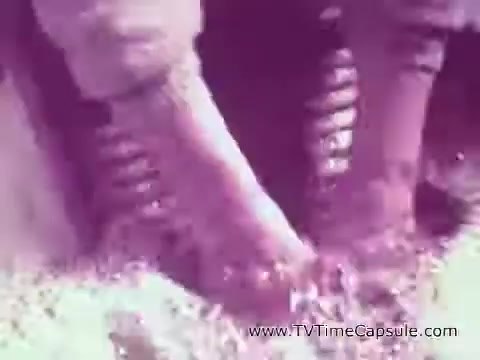 The still from the 'ScotTowels Commercial' depicts a close-up of feet in a wet environment, likely emphasizing the absorbency and effectiveness of ScotTowels. The colors appear soft and slightly muted, creating a nostalgic feel typical of vintage commercials. The focus on the feet suggests a functional use case, highlighting the product's practicality.