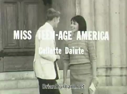 The still from the 1968 Ford 'Miss Teenage America' PSA features a young man and a young woman interacting outdoors, with the title 'MISS TEEN-AGE AMERICA' prominently displayed in white text. The scene appears affected by vinegar syndrome, giving it a distorted and aged look. The overall vibe reflects the fashion and cultural norms of the late 1960s.