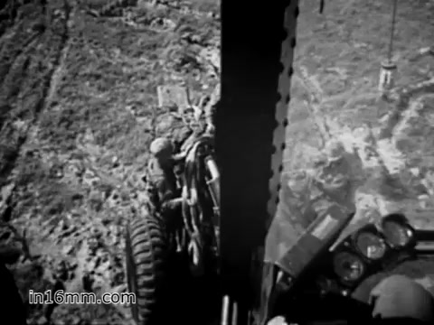 The still from 'Your Man in Vietnam' (1968) features a close-up view of a CH-54 helicopter, emphasizing its operational role and the challenges faced by U.S. Army personnel like James Daly, a flight engineer. The scene captures the rugged terrain and the vehicle's heavy-duty capabilities, showcasing the helicopter's function in transporting military equipment. The black-and-white imagery evokes a historical context, highlighting the realities of Vietnam War logistics.