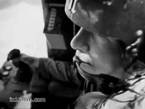 The still from 'Your Man in Vietnam' features a close-up of a soldier, likely James Daly, operating a control panel. He appears focused and determined, wearing a helmet typical of the era. The context emphasizes his role as a flight engineer for the CH-54 helicopter, highlighting both the innovative machinery and the rugged demands of his service. This moment captures the intensity of a soldier’s experience during the Vietnam War, illustrating the critical responsibilities involved in military aviation.