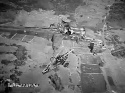 The still from 'Your Man in Vietnam' features a CH-54 helicopter, prominently showcasing its rugged design and utility. It highlights the aircraft in action, likely transporting heavy equipment like tractors or artillery, emphasizing its role and capability in the Vietnam War. The background suggests a military landscape, reinforcing the operational context. The focus is on the helicopter's functionality, illustrating the demands placed on it and the skill involved in its operation.