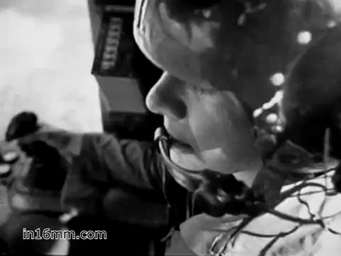 The still from 'Your Man in Vietnam' features a close-up of a young soldier, likely James Daly, in a flight engineer's helmet, focused on his work. The background suggests a helicopter environment, emphasizing the role of the CH-54, a heavy-lift helicopter. The image captures the soldier's determination and dual responsibilities of operating and maintaining the aircraft while also transporting essential military equipment. The overall tone reflects the intensity and challenges of military life during the Vietnam War era.