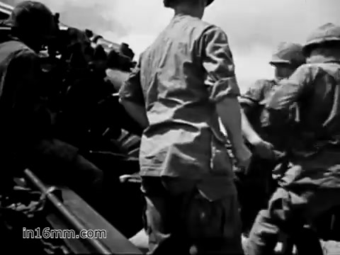The still from 'Your Man in Vietnam' depicts U.S. Army soldiers engaged in activity, likely related to military operations. The black-and-white imagery reflects the gritty conditions of the Vietnam War era. These soldiers may be transitioning equipment or preparing for a mission, embodying the logistical aspects of military life highlighted in the accompanying voiceover about the responsibilities of a flight engineer, specifically in relation to the CH-54 helicopter. The focus on practical duties and teamwork emphasizes the operational challenges faced in the field.