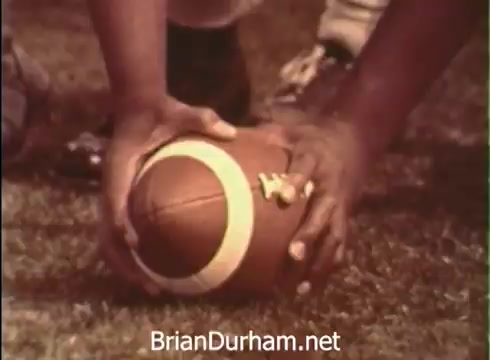 The still features a close-up of hands gripping a football on a grassy field, symbolizing a transition from college sports to a career in aerospace with the United States Air Force. The contrasting imagery reflects the journey from academia and athletics to serving in a high-tech military role, emphasizing teamwork and progress.