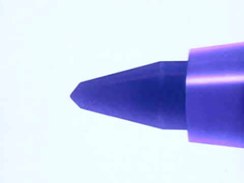 The still captures the pointed tip of a Flair pen, prominently showcasing its distinctive design. The angle highlights the purple plastic casing and the innovative point guard feature, a key selling point implying durability and precision. The stark background enhances focus on the pen, emphasizing its functionality. This moment underscores the commercial's core message: reliability without mushing down.   Follow us on Twitter @FromFilm for more insights!