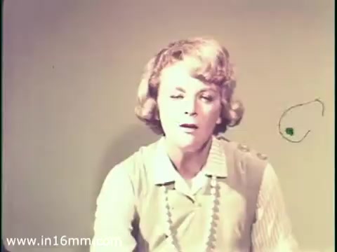 The still features a woman with short, curly hair, wearing a light-colored blouse and a necklace. She appears to be in a serious or concerned state, likely delivering a message about measles and its potential impact on mental disability. The background is a plain, muted color, focusing attention on her expression and the importance of the topic being discussed. This imagery is characteristic of public service announcements from the late 1960s, emphasizing health awareness.