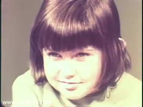 The still from the 1968 PSA depicts a young girl with a bob haircut and a slight smile. She appears to be the focus of the scene, conveying innocence and curiosity. The image likely aims to evoke emotional responses regarding the importance of measles vaccination and its connection to preventing mental disabilities. The warm color palette and soft lighting enhance the PSA's message about child health and safety.