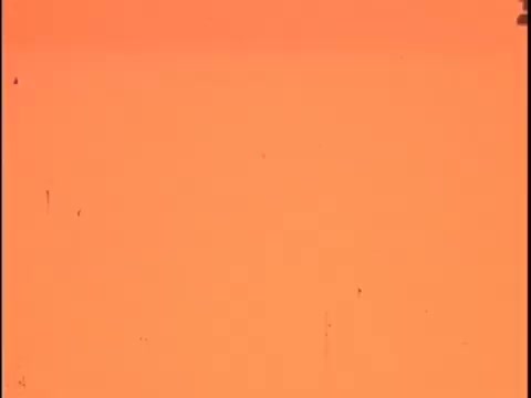 The still from the 'Koogle Flavored Peanut Butter' commercial negative is characterized by a washed-out, orange tint typical of film negatives. It likely includes visual elements like countdown leader markers and a 'China Girl' slate, which indicate the start of frames and help sync sound during editing. The overall appearance suggests it’s an early commercial production, possibly with noticeable scratches or dirt, which can be cleaned up during the restoration process. Focus on correcting color balance and restoring clarity to convey the original vibrancy of the final product.