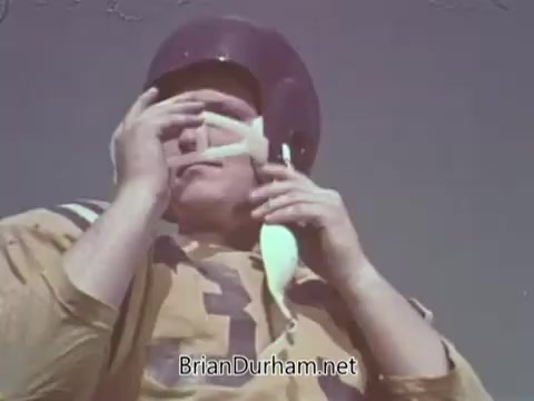 The still features a muscular man in a football uniform and helmet. He is adjusting a white mouthpiece or protective gear, suggesting a focus on safety in sports. The color palette and style reflect the 1960s, aligning with the theme of the Automotive Safety Foundation's public service announcement. The image emphasizes the importance of protection in high-impact activities.