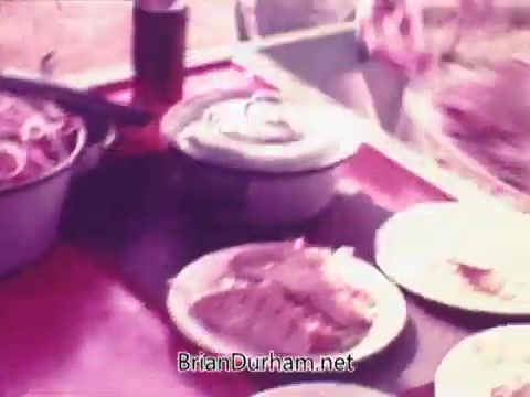 The still from the Pepsi commercial 'Todos junto a Pepsi siempre libre y feliz' features a colorful display of food items served on plates and in bowls. The atmosphere appears inviting, suggesting a communal or festive dining experience, possibly promoting a sense of togetherness and enjoyment associated with Pepsi. The color tone is warm, enhancing the overall appeal of the scene.