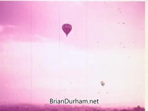 The still features two hot air balloons floating against a predominantly pink sky. The scene evokes a sense of freedom and happiness, aligning with the commercial's theme of togetherness and joy associated with Pepsi. The soft colors and airy atmosphere suggest a lighthearted and whimsical mood.