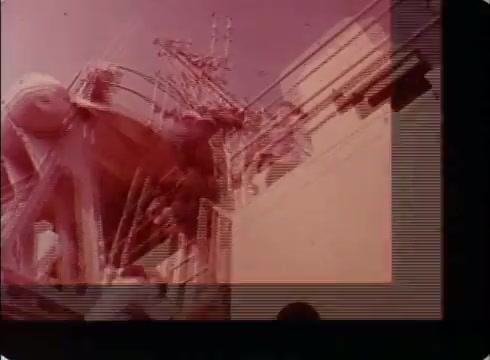 The still from the PSA features a scene likely depicting military personnel engaged in operations involving machinery or equipment on a ship or a similar structure. The image has a reddish tint, indicative of the era's film style. It emphasizes the active role of the National Guard and Reserves during the 1970s, showcasing teamwork and readiness.