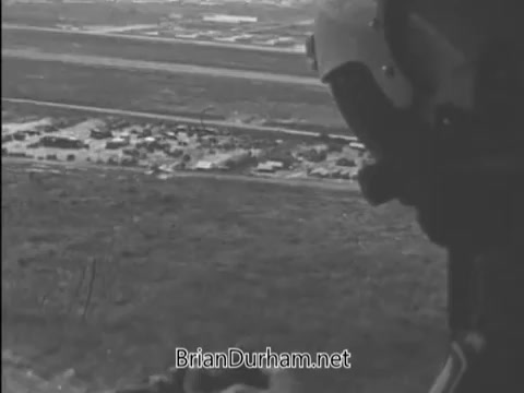 The 16mm still from the 'Buy Bonds PSA - Vietnam Era - 1968' depicts a helicopter's perspective over a landscape, likely showcasing military or war-related imagery. The focus is on the view from the helicopter, emphasizing the connection to the Vietnam War and the call to action for purchasing bonds to support military efforts. The tone is serious, reflecting the era's context.