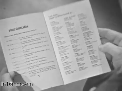 The still features a person holding an open booklet titled 'your timetable.' The pages appear to contain a list of resources or schedules related to services provided by the Veterans Administration, emphasizing important information for veterans. The black-and-white image captures a moment of engagement with the material, likely aimed at conveying support and guidance for veterans in the 1960s.