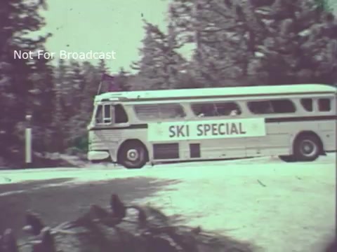 The still from the 1970 Hormel Chili TV commercial features a vintage bus labeled 'SKI SPECIAL' driving along a road. Surrounding the bus are trees, suggesting a natural, possibly mountainous environment, typical for ski destinations. The overall aesthetic is nostalgic, reflecting the era's film quality and style.