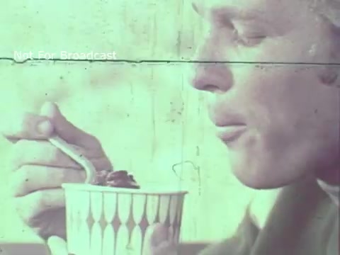 The still from the 1970 Hormel Chili TV commercial features a close-up of a man savoring a bowl of chili. He is holding a spoon and appears to be enjoying the meal, with a thoughtful expression. The color palette is muted, typical of 16mm film, giving it a vintage feel. The text overlay indicates that it's not for broadcast, emphasizing its archival nature. The imagery captures the essence of the era while promoting the product.