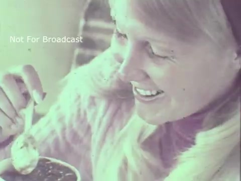 The still features a smiling woman enjoying a bowl of Hormel Chili, holding a spoonful of the chili close to her mouth. She is dressed warmly, suggesting a cozy atmosphere. The vintage quality of the 16mm print adds a nostalgic feel to the scene. Text overlay indicates that this image is not for broadcast.