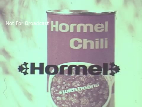 The still features a vintage can of Hormel Chili prominently displayed. The can is labeled 'Hormel Chili' and includes the phrase 'with beans.' The overall aesthetic reflects the 1970s advertising style, with a soft focus and a nostalgic color palette, emphasizing the brand's identity. The watermark 'Not For Broadcast' indicates it’s not intended for public viewing.