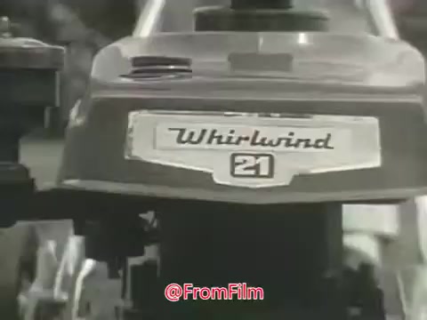 The still showcases a Toro Whirlwind lawnmower, prominently featuring the model name 'Whirlwind 21' on its engine cover. The design reflects the 1960s aesthetic, emphasizing utilitarian features and robust construction. The image is likely characteristic of promotional materials targeting homeowners seeking efficient lawn care solutions.