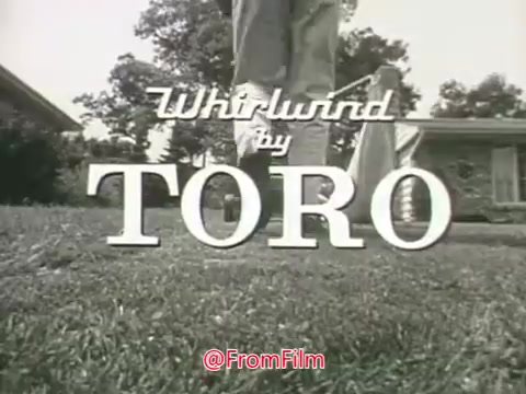 The still from the 1960s Toro Whirlwind Lawnmower commercial features a close-up of the lawnmower’s branding. The title 'Whirlwind by TORO' is prominently displayed in a stylized font, emphasizing the product. In the background, a well-maintained lawn and a suburban home are visible, reflecting the idealized outdoor setting typical of lawn care advertisements from that era. The overall monochrome aesthetic suggests a vintage quality, characteristic of 16mm film.