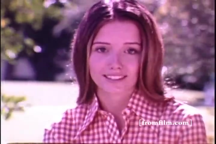 The still features a young woman smiling, wearing a classic checkered shirt, against a blurred outdoor background. The colors are soft and slightly faded, typical of a 16mm film print from the 1970s. The scene conveys a cheerful and approachable vibe, likely intended to promote the Ivory Soap brand in a nostalgic setting.