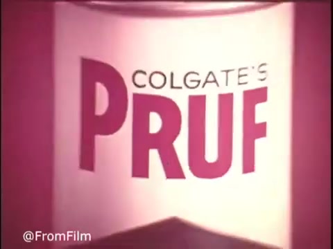 The still features the logo for Colgate's Pruf Spray Starch, presented prominently in bold, stylized typography. The color scheme is vibrant, with a bright backdrop that emphasizes the product. The design reflects a classic 1970s aesthetic, evoking nostalgia for vintage advertising. The branding conveys a sense of reliability and household familiarity.