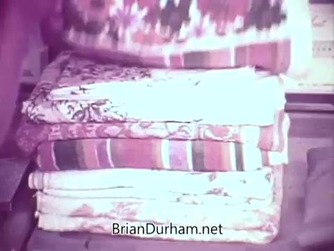 The still shows a neat stack of brightly colored towels, including floral and striped patterns. The setting seems to emphasize cleanliness and freshness, typical of a detergent commercial, likely highlighting the effectiveness of Cold Power detergent in maintaining vibrant colors.
