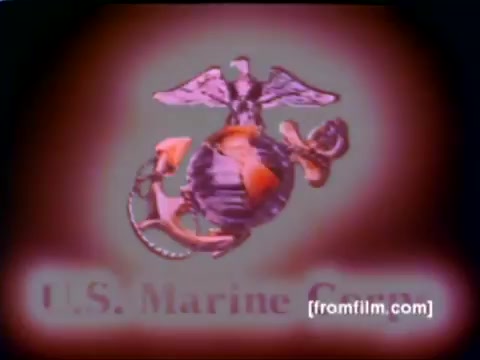 The 16mm still from the 'USMC Aviation Ordnance enlistment film' showcases a striking emblem of the U.S. Marine Corps, prominently featuring the eagle, globe, and anchor symbol, rendered in vivid colors. The film context highlights various military aircraft including F-4 Phantoms, AH-1 SuperCobras, an FA-18, and a Harrier, along with scenes of ordnance being mounted, such as missiles and bombs. The overall tone suggests a focus on the technical aspects of Marine aviation and the significance of ordnance in operational readiness.