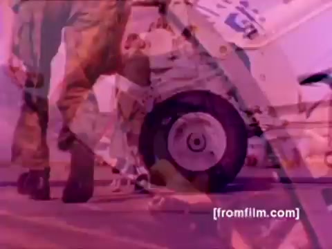 The still from the 'USMC Aviation Ordnance enlistment film' features a vivid portrayal of Marine Corps activities. It showcases F-4 Phantoms, AH-1 SuperCobras, an FA-18, and a Harrier, all of which highlight military aviation technology. The scene likely focuses on ordnance specialists mounting missiles and bombs onto aircraft.   Due to the medium's vintage nature, the colors may require correction for a clearer representation, emphasizing the dynamic and intense environment of military aviation operations. The overall composition captures the spirit of enlistment and the essential role of ordnance in Marine Corps aviation.